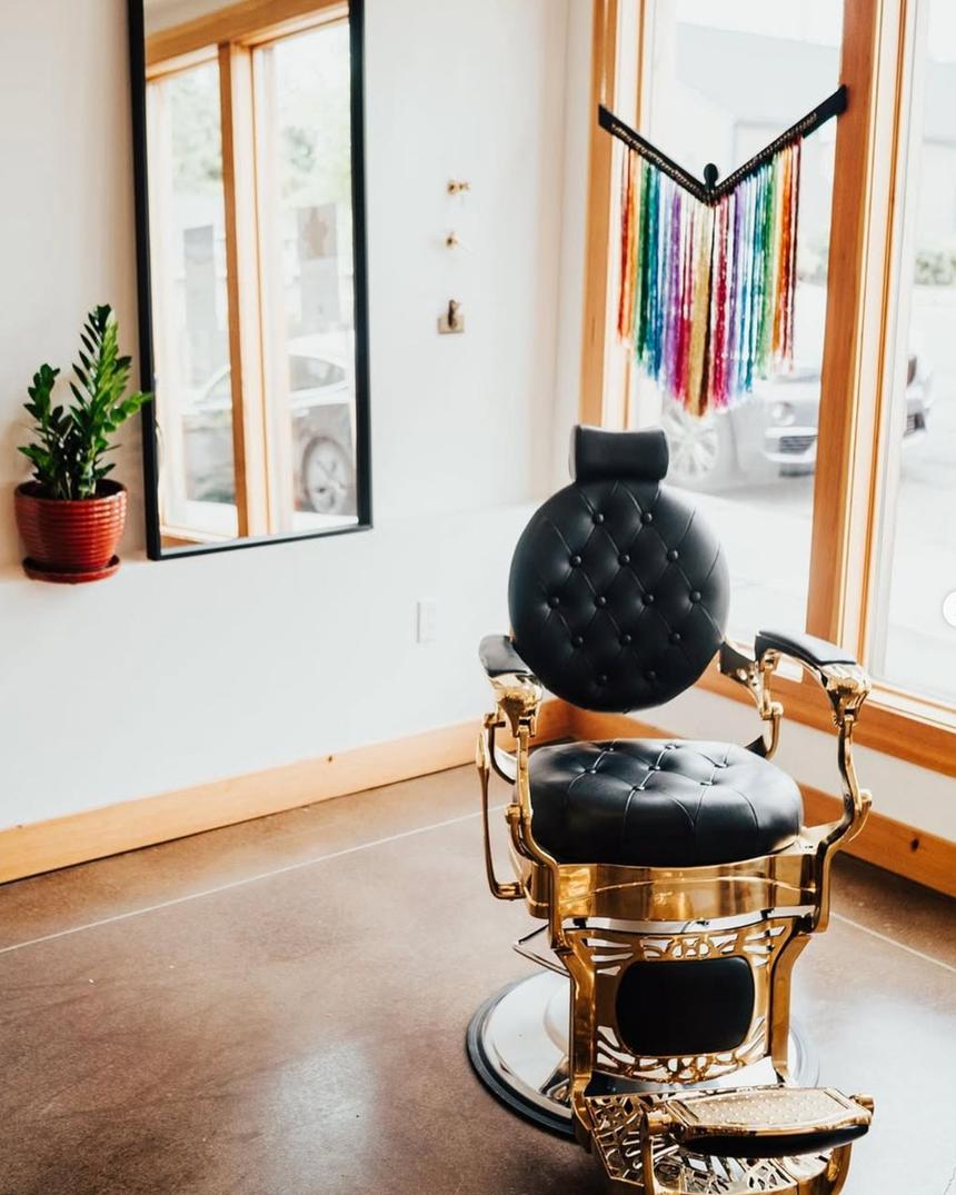 An antique gold barber chair by a bright window, sparkle colors hung in the light