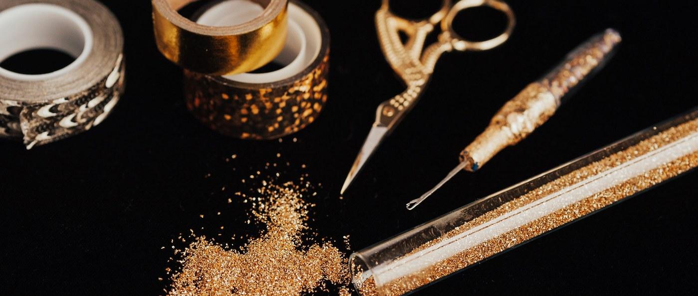 The tools laid out: gold scissors, the tying hook, tape and a vial of glitter