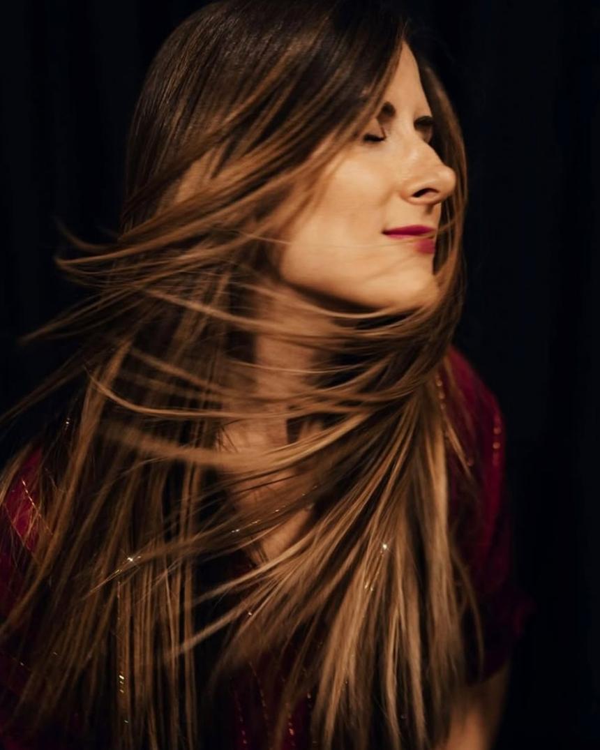 Long hair mid-turn against a dark backdrop, fine sparkle strands catching the light