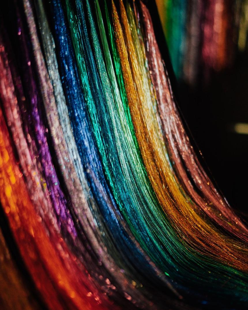 Rows of sparkle strands hung by color, red through gold to silver